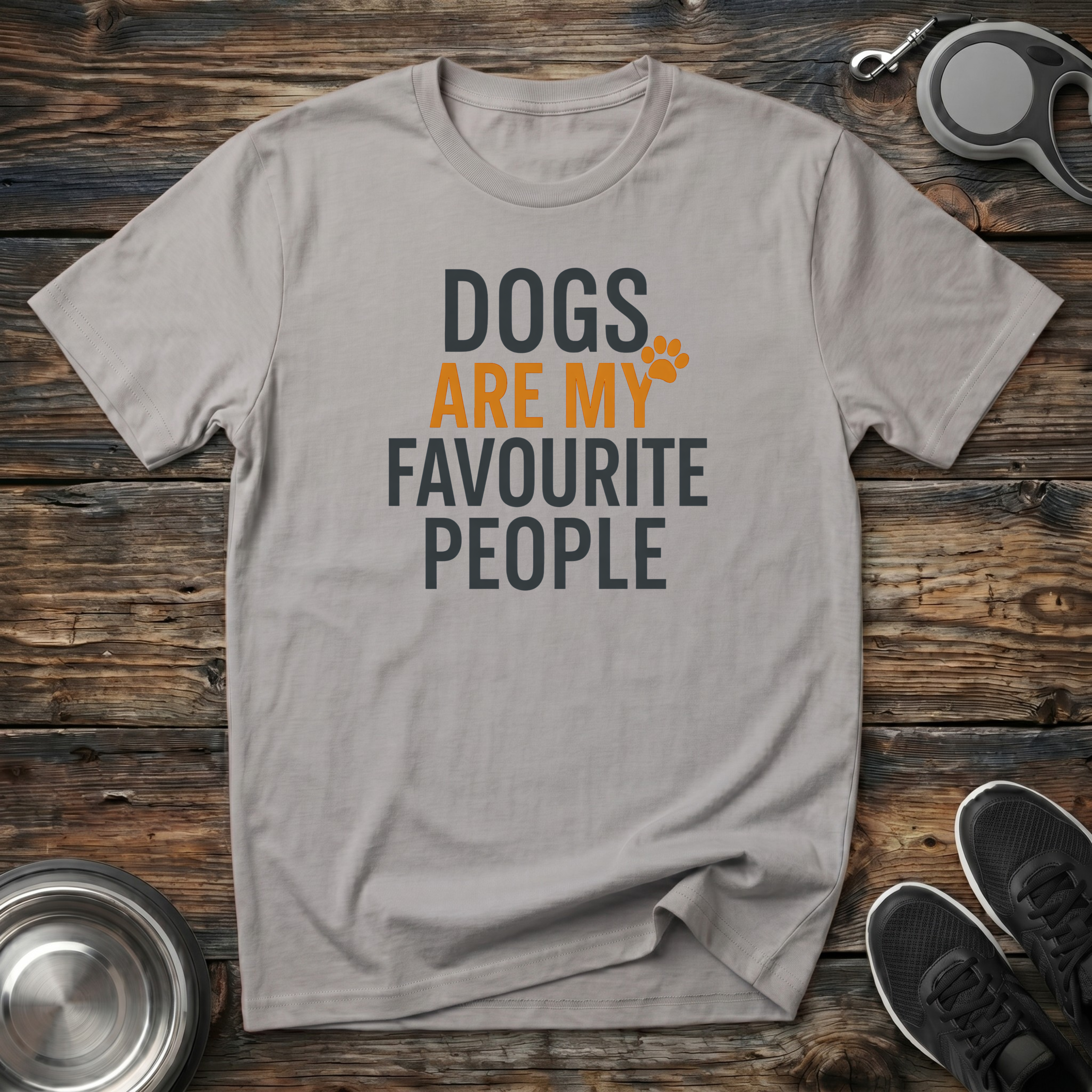 Light taupe unisex t-shirt with bold charcoal and amber block text reading "Dogs Are My Favourite People" with an orange paw print accent — funny dog lover gift tee