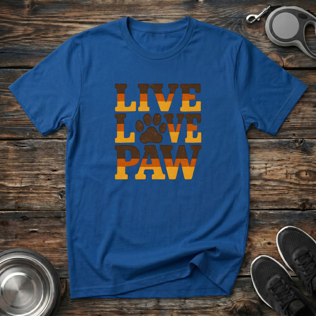 Royal blue unisex t-shirt with bold retro groovy "Live Love Paw" stacked block lettering in burnt orange and golden amber gradient with distressed paw print replacing the letter O — warm dog lover gift tee