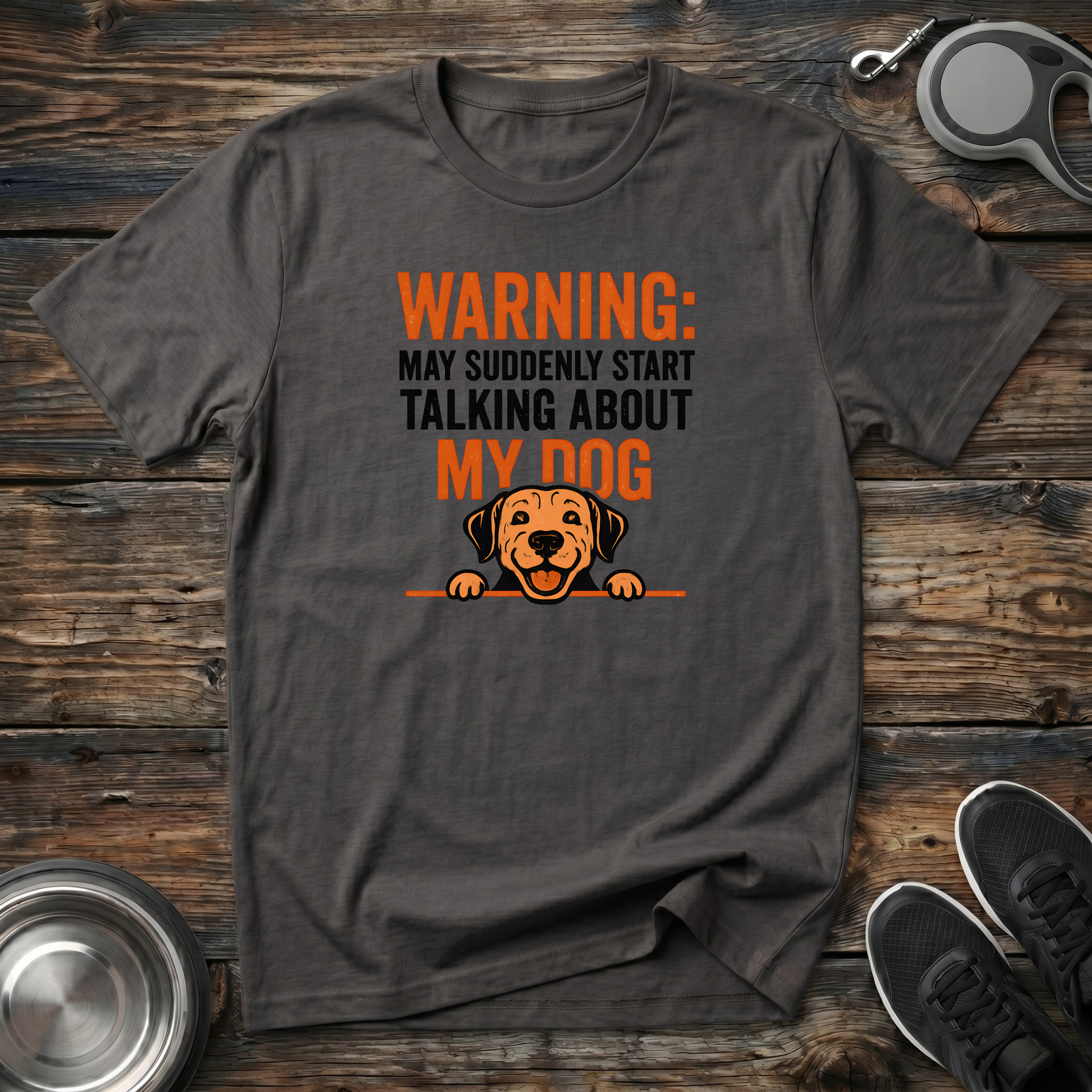 Dark charcoal heather unisex t-shirt with bold orange and black "Warning: May Suddenly Start Talking About My Dog" lettering and cute peeking dog face graphic — funny dog lover gift tee