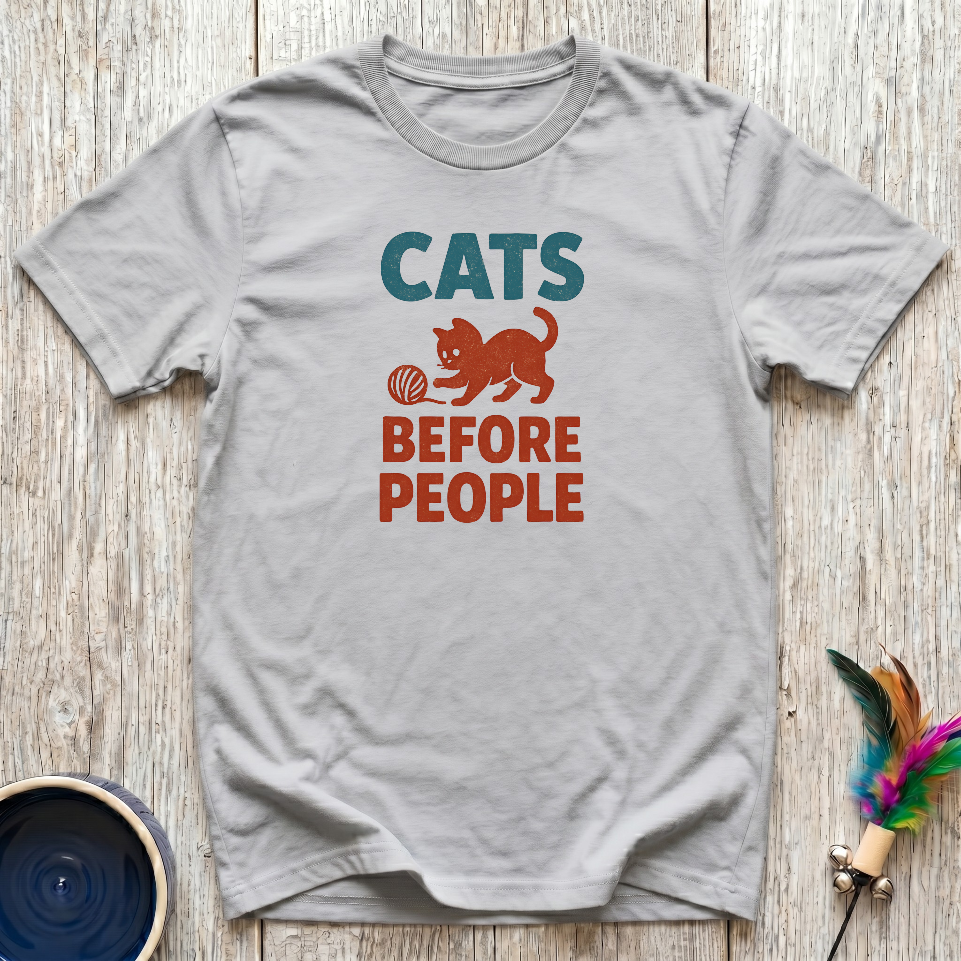 Soft grey unisex t-shirt with bold teal "Cats" and burnt orange "Before People" retro block lettering and vintage cat playing with yarn graphic — funny cat lover gift tee for introverts