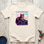 Cream unisex t-shirt with retro tabby cat wearing sunglasses on a boombox graphic and colorful "Caturday Vibes" neon lettering — funny cat lover gift tee
